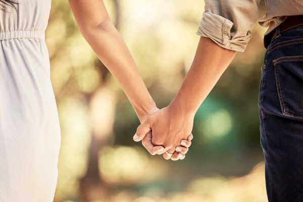 A happy couple holding hands and smiling during a premarital counselling session with a therapist in Singapore. The therapist is guiding them through meaningful discussions to strengthen their relationship before marriage.